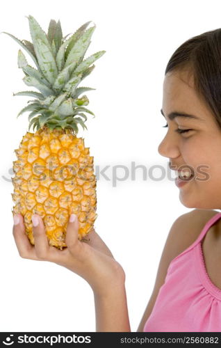 Young girl holding pineapple and smiling