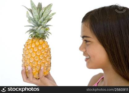 Young girl holding pineapple and smiling