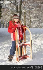 Young Girl Holding Sledge In Snowy Landscape