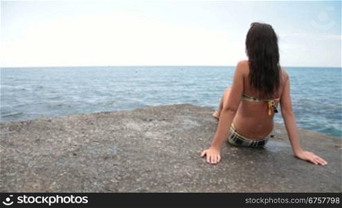young girl in a bikini sunbathing on the pier