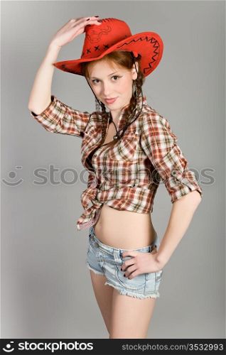 young girl in a checkered shirt and a red cowboy&rsquo;s hat