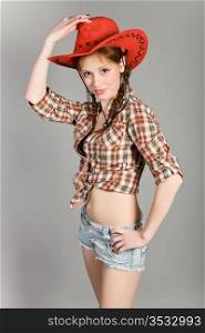 young girl in a checkered shirt and a red cowboy&rsquo;s hat