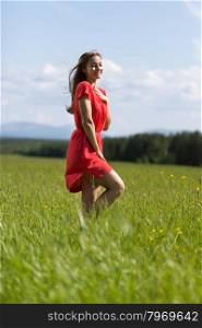Young girl in a red dress in a field on a day