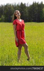 Young girl in a red dress in a field on a sunny day