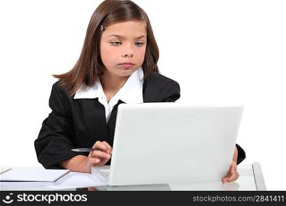 Young girl in a suit working at a laptop