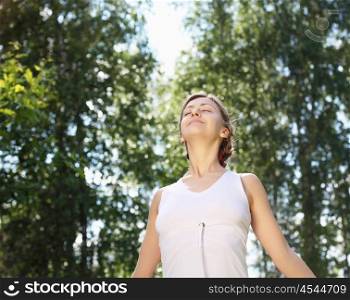Young girl in a white shirt and red pants doing sport exercises in nature