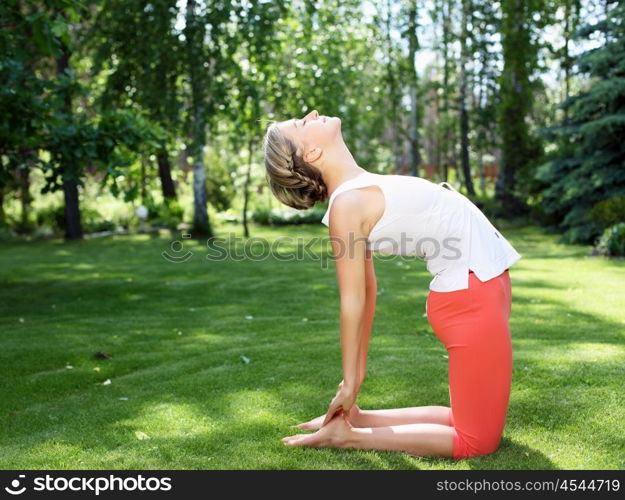 Young girl in a white shirt and red pants doing yoga outdoors