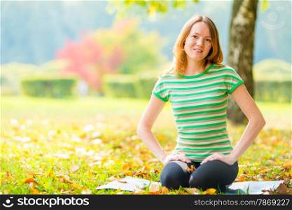 young girl in autumn park in the morning practicing yoga
