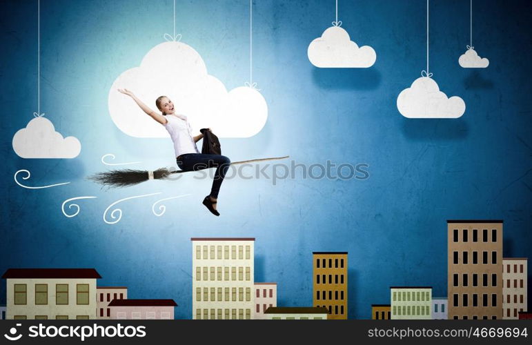 Young girl in casual flying on broom high in sky. Girl on broom