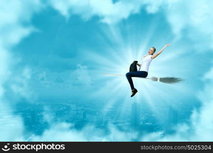 Young girl in casual flying on broom high in sky. Girl on broom