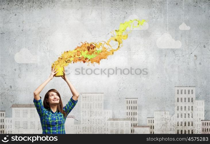 Young girl in casual splashing colorful paint from bucket