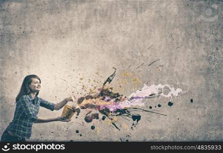 Young girl in casual splashing colorful paint from bucket