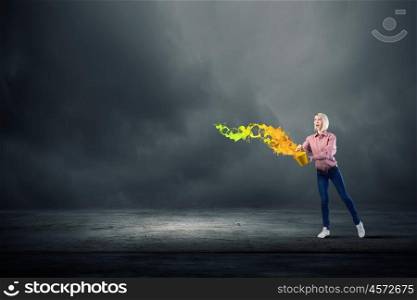Young girl in casual splashing colorful paint from bucket. Add some color to your life