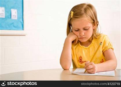 Young Girl in Classroom Writing on Paper