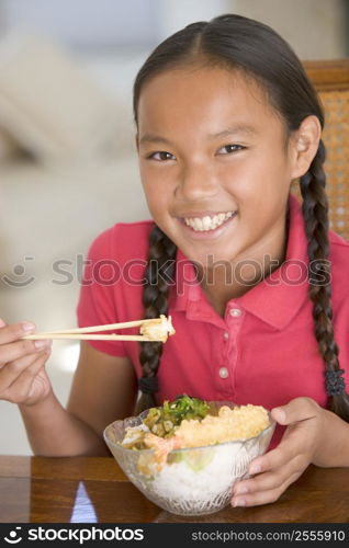 Young girl in dining room eating Chinese food smiling