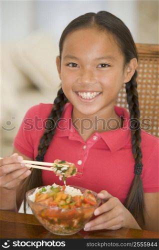 Young girl in dining room eating chinese food smiling