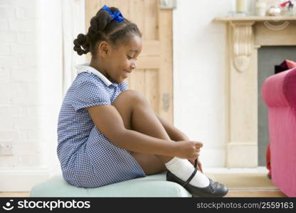 Young girl in front hallway fixing shoe and smiling