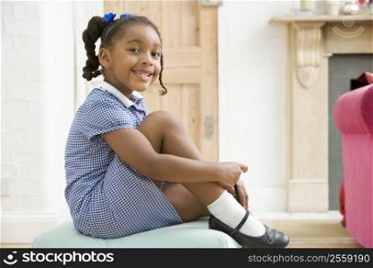 Young girl in front hallway fixing shoe and smiling