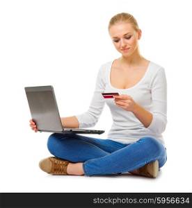 Young girl in jeans with laptop and credit card isolated