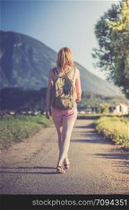 Young girl in jumpsuit with backpack is taking a walk, summer time