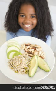 Young girl in kitchen eating rice fruit and nuts smiling