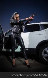 Young girl in leather clothes with gun