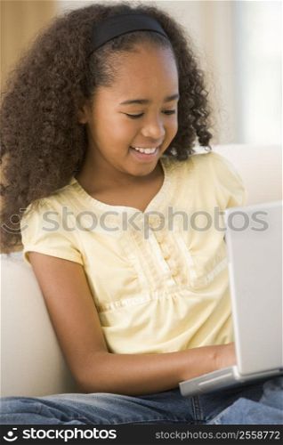 Young girl in living room using laptop and smiling