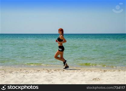 young girl in sportswear jogging on a deserted sea coast. girl running seaside