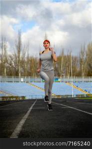 young girl in sportswear jogging through a deserted stadium. Girl is engaged in jogging