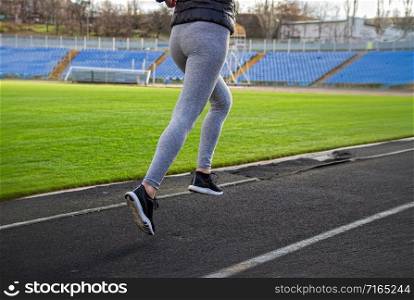 young girl in sportswear jogging through a deserted stadium. Girl is engaged in jogging