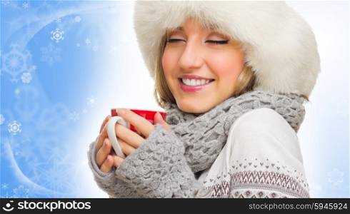Young girl in sweater and fur cap with mug