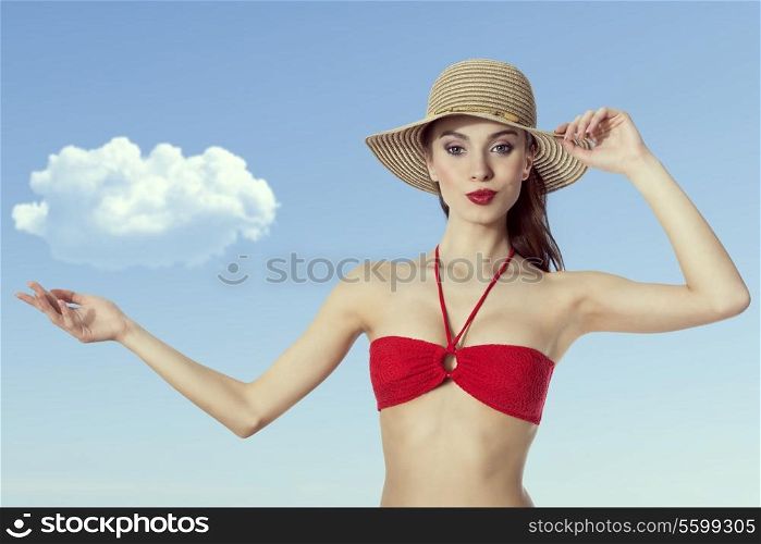 Young girl in swimsuit is holding hat and pointing a cloud by hand . with expresssion on face. Summer time