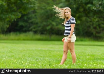 Young girl in the park and wind waves her hair, image with narrow depth of field
