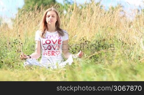 Young girl in white t-shirt meditating in the city park.