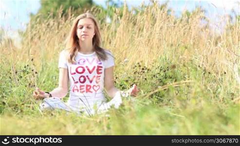 Young girl in white t-shirt meditating in the city park.