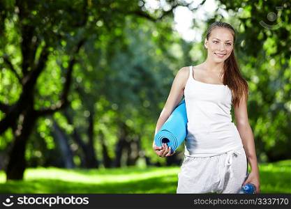 Young girl in white with a bottle of water and gymnastic mat