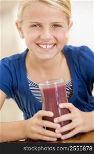 Young girl indoors drinking juice smiling