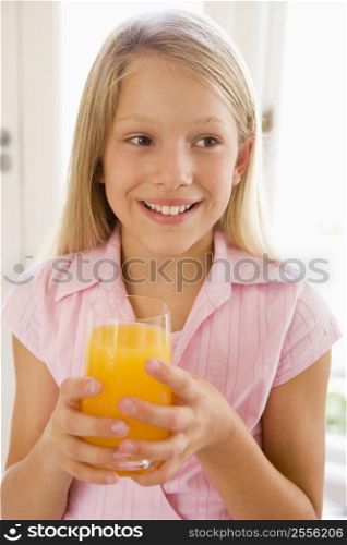 Young girl indoors drinking orange juice smiling