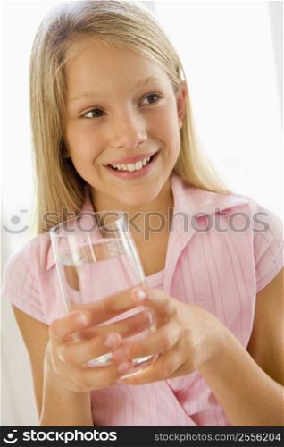 Young girl indoors drinking water smiling
