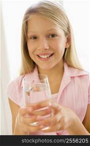 Young girl indoors drinking water smiling