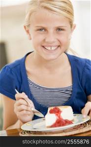 Young girl indoors eating cheesecake smiling
