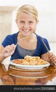 Young girl indoors eating fish and chips smiling