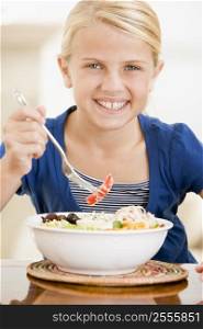 Young girl indoors eating seafood smiling
