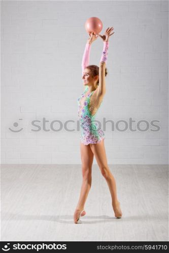 Young girl is engaged in art gymnastics on grey