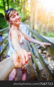 Young girl is holding her hand to her boyfriend, outdoors in the woodland