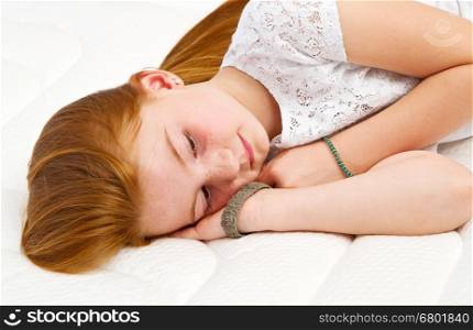 Young girl is lying on the bed. Quality mattress.