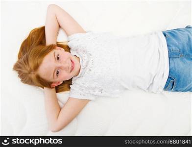 Young girl is lying on the bed. Quality mattress.
