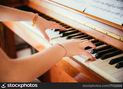 Young girl is practicing piano at home. Clipping of piano and hands.
