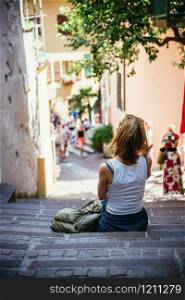 Young girl is sitting on the stony stairs, Italian village, summer holidays