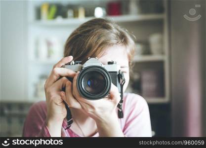 Young girl is taking a picture with a vintage camera